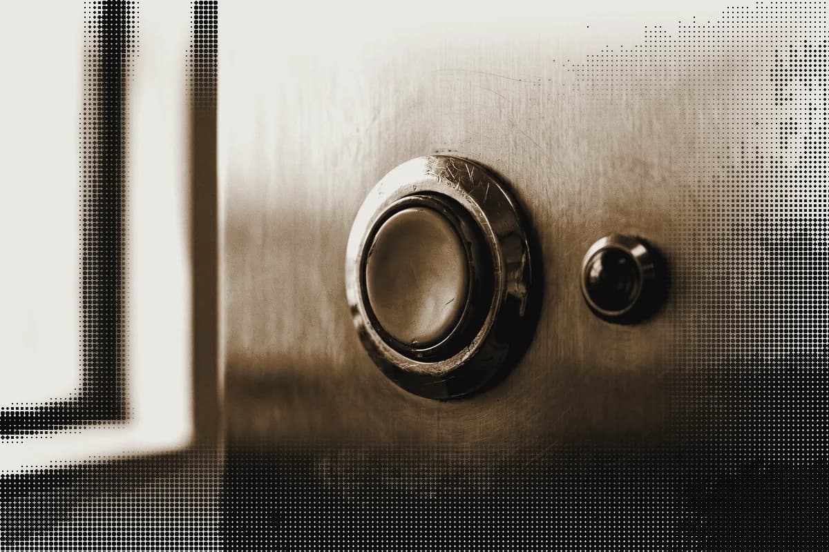 A worn mechanical push button set into a steel panel, one small indicator lamp beside it, pressed in bronze